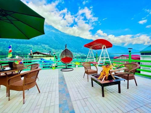 un patio con sillas, mesas y una sombrilla en TATA Vista Resort Mall Road Manali - Centrally Heated & Air Cooled, en Manali