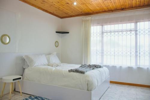 a white bedroom with a large bed and a window at Lake Acres Guest House in Kokstad