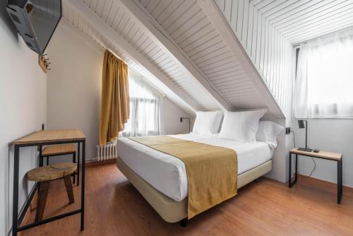 a bedroom with a large white bed and a window at Hotel Viella in Vielha