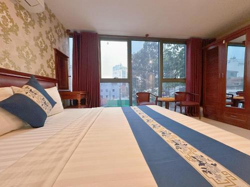 ein Schlafzimmer mit einem großen Bett und einem großen Fenster in der Unterkunft Kim Dung Hotel Tran Quang Khai in Ho-Chi-Minh-Stadt