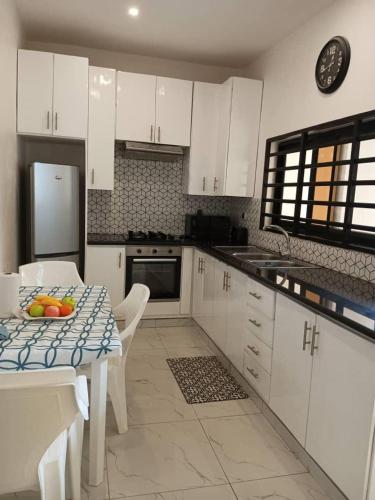 una cucina con armadi bianchi e un tavolo con frutta di Villa luxueuse ad Abomey-Calavi