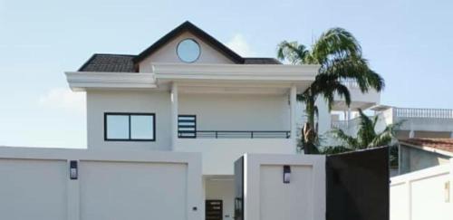 a white house with two garage doors and a palm tree at Villa luxueuse in Abomey-Calavi
