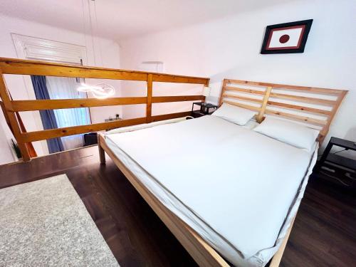 a bedroom with a wooden bed with white sheets at Vibrant center apartment in Budapest