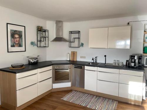 a kitchen with white cabinets and stainless steel appliances at Ferienwohnung Achenrain 1 in Kramsach