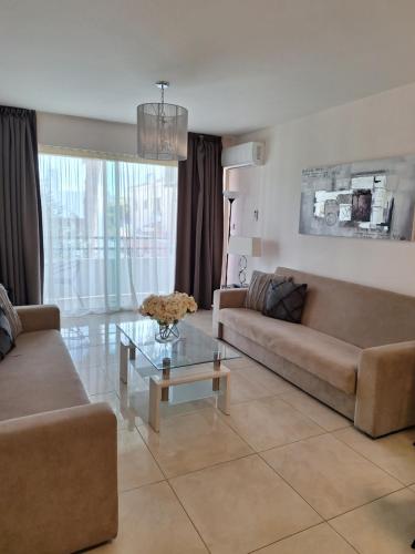 a living room with two couches and a glass table at Marianna Hotel Apartments in Limassol