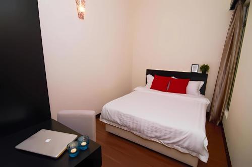a bedroom with a bed with red pillows and a laptop at BY LG Resort & Water Park Melaka in Malacca