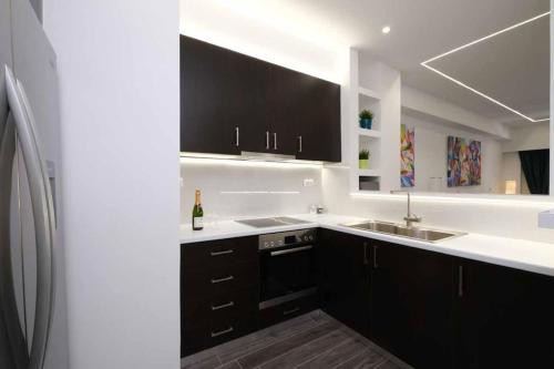 a kitchen with black cabinets and a sink at Athenian Comfort Haven in Athens