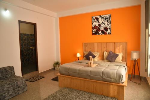 1 dormitorio con 1 cama con pared de color naranja en Himtrek Stays, Kasol en Kasol