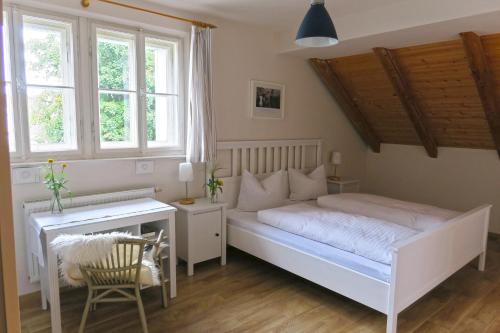 a bedroom with a bed and a desk and windows at Pension Schönhuber in Mainburg