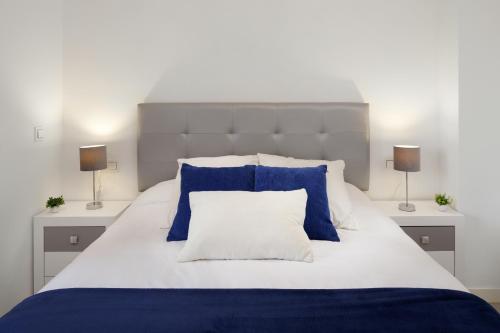 a bed with blue and white pillows and two lamps at Playamarinsa in Torre del Mar