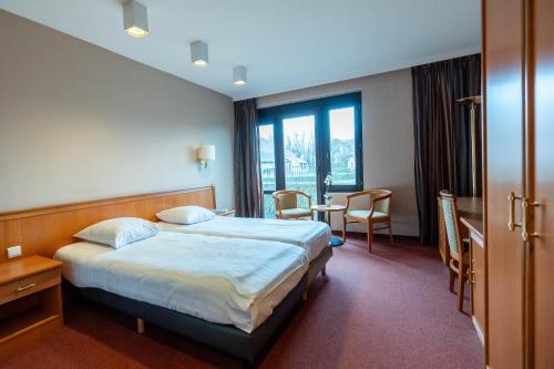 um quarto de hotel com uma cama, uma mesa e cadeiras em Corsendonk Duinse Polders em Blankenberge