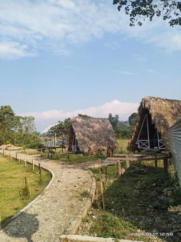 a path leading to two thatch huts with a road at Wood Town Resort in Kharem