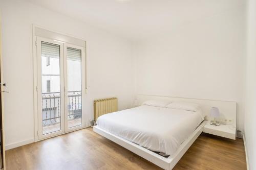 a white bedroom with a bed and a window at Casa Olegari 