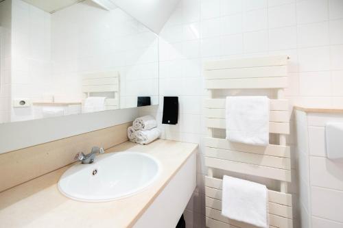 uma casa de banho branca com um lavatório e um espelho em Corsendonk Duinse Polders em Blankenberge