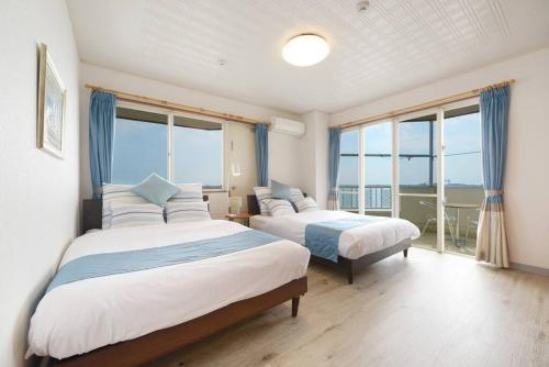 two beds in a room with large windows at ライカムまで車で7分 オーシャンビュー付き 最大8人 駐車場2台 長期滞在にもおすすめ MK1 in Okinawa City