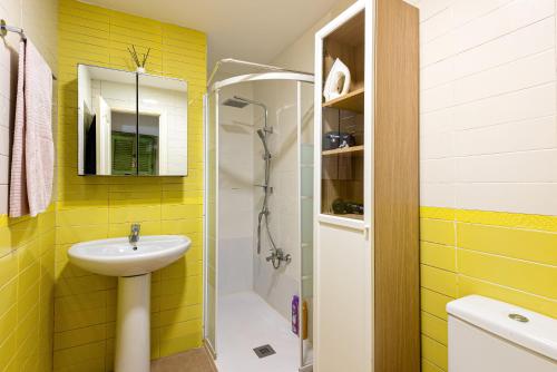 y baño amarillo con lavabo y ducha. en Casita playa, en Málaga
