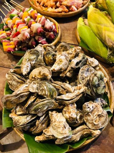a table with plates of oysters and a salad at Cóc Retreat Mỹ Tho City in My Tho