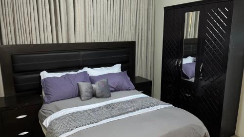 a bed with purple pillows in a bedroom at Estadia alegre ao som do mar in Maputo