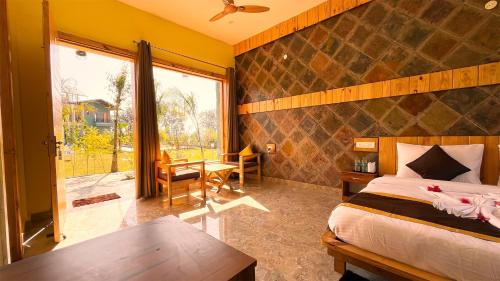 een slaapkamer met een bed, een bureau en een raam bij Corbett Nirvana Resort in Rāmnagar