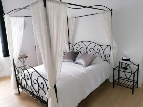 een slaapkamer met een zwart hemelbed en witte gordijnen bij Château de Saint-Genix in Saint-Genix-sur-Guiers