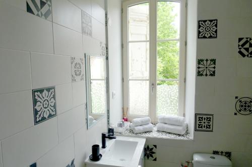 een badkamer met een wastafel, een spiegel en een raam bij Château de Saint-Genix in Saint-Genix-sur-Guiers