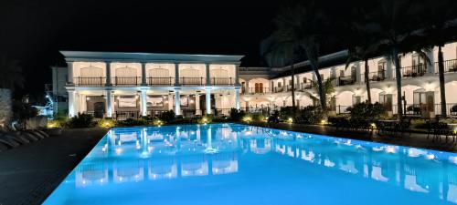 une grande piscine devant un immeuble la nuit dans l'établissement Lagoon Sarovar Premiere Resort - Pondicherry, à Pondichéry