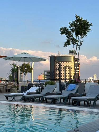 a swimming pool with lounge chairs and an umbrella at Hotel Sun in North Nicosia