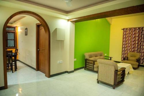 a living room with a green wall and chairs at 2BHK Modern Suites in North Goa in Saligao