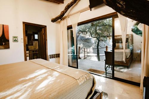a bedroom with a bed and a large window at Boskenvid Hotel - Romantic Treehouses & Skypool in Valle de Guadalupe