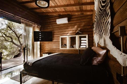 um quarto com uma cama num chalé de madeira em Boskenvid Hotel Boutique, Skypool em Valle de Guadalupe