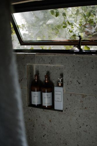 three bottles sitting on a shelf in a window at Boskenvid Hotel - Romantic Treehouses & Skypool in Valle de Guadalupe