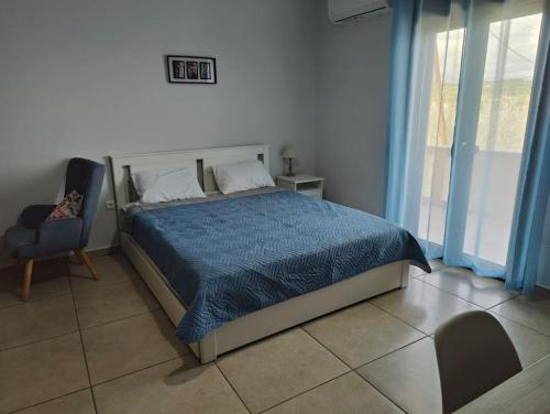 a bedroom with a bed with a blue comforter and a chair at Varkaris Room 1 in Katarráktis