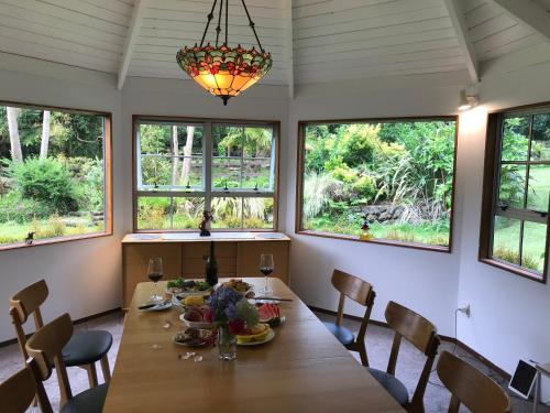 a dining room with a table and chairs and windows at Horse Shoe Manor in Paihia