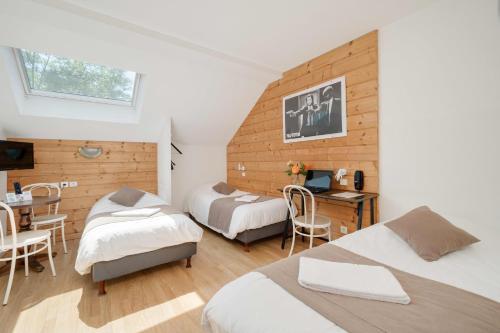 a bedroom with two beds and a desk and a table at Hôtel Acacia Nancy sud Lunéville in Lunéville