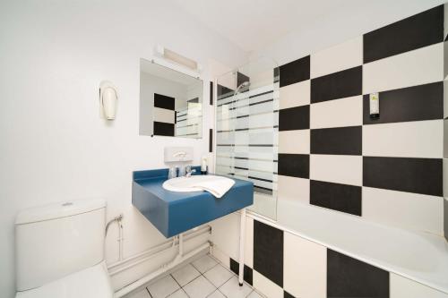 baño con pared a cuadros en blanco y negro en Hôtel Acacia Nancy sud Lunéville en Lunéville