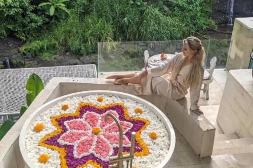 a woman sitting on a table next to a large crochet rug at Villa Cella Bella Ubud in Ubud