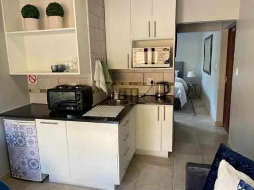 uma cozinha com armários brancos e um balcão preto em 642 on Vincent em Pretoria