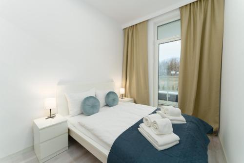 Un dormitorio blanco con una cama con toallas. en Apartament Przystań Ku Morzu by HolidaySun en Sianozety