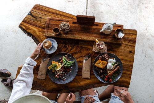 Un grupo de personas sentadas alrededor de una mesa de madera con comida. en The Bearded Dragon Boutique Hotel, en Mount Tamborine