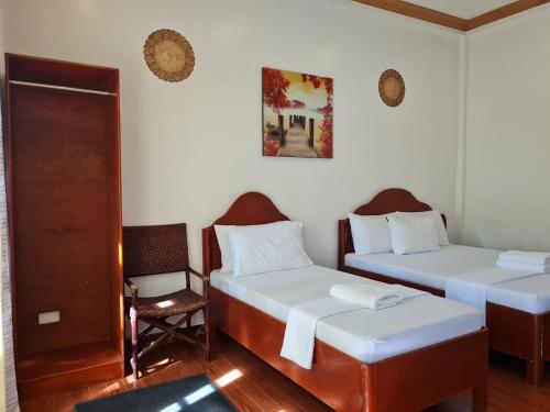 a room with two beds and a chair in it at Alona Hidden Dream Resort by SMS Hospitality in Panglao
