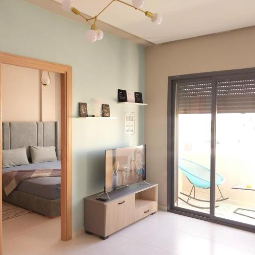 a bedroom with a bed and a tv and a balcony at appartement moderne proche aéroport in Derroua