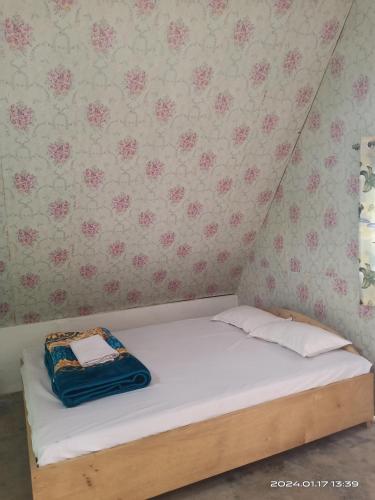 a small bed in a room with pink flowers on the wall at Wood Town Resort in Kharem