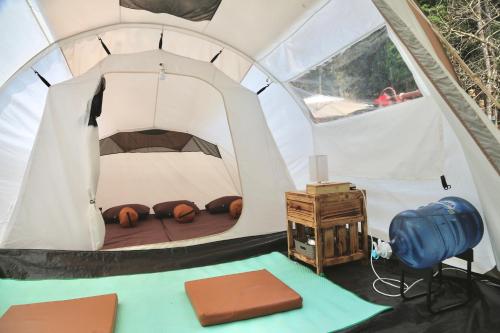 Zelt mit einem Bett und einem Tisch in der Unterkunft SoraCai Riverside Campsite in Palayangan