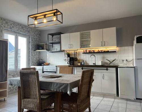 une cuisine avec une table avec des chaises et un réfrigérateur dans l'établissement 207 - Jolie maison mitoyenne entre terre et mer en campagne de Plurien, à Plurien