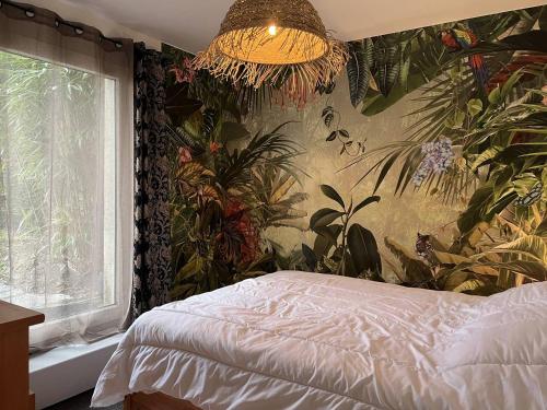ein Schlafzimmer mit einer Pflanzenwand mit einem Bett und einem Kronleuchter in der Unterkunft 207 - Jolie maison mitoyenne entre terre et mer en campagne de Plurien in Plurien