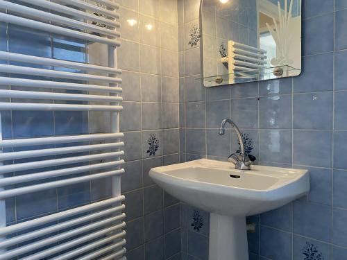 ein blau gefliestes Bad mit einem Waschbecken und einem Spiegel in der Unterkunft 207 - Jolie maison mitoyenne entre terre et mer en campagne de Plurien in Plurien