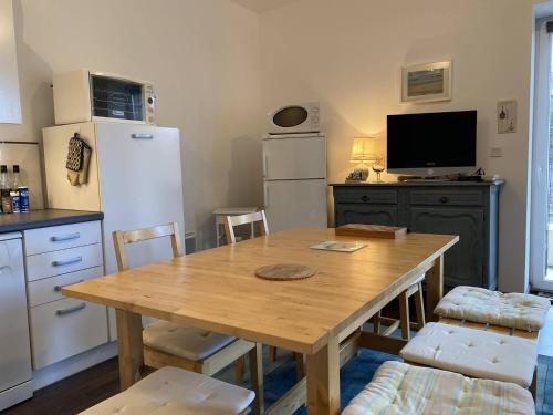 a kitchen with a wooden table and a refrigerator at 359 - Appartement T3, à deux pas de la plage l'Anse du Croc et de sa vue sur le Cap Fréhel in Frehel