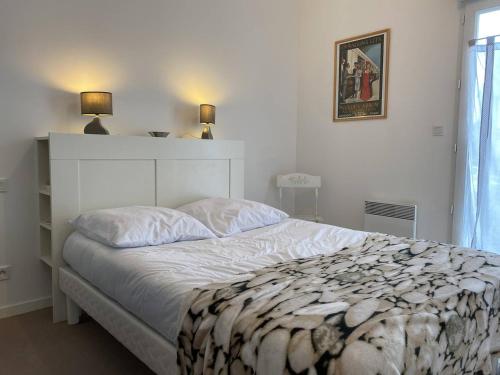 a bedroom with a large white bed with two lamps at 359 - Appartement T3, à deux pas de la plage l'Anse du Croc et de sa vue sur le Cap Fréhel in Frehel