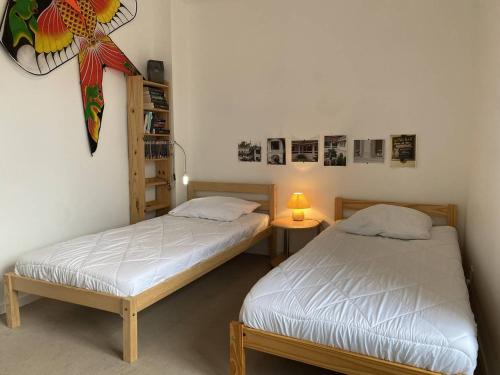 two beds in a room with a lamp and a shelf at 359 - Appartement T3, à deux pas de la plage l'Anse du Croc et de sa vue sur le Cap Fréhel in Fréhel