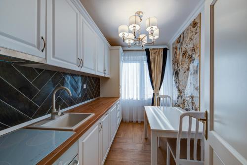 a kitchen with white cabinets and a sink at Montana Popa ApartHotel in Blaj